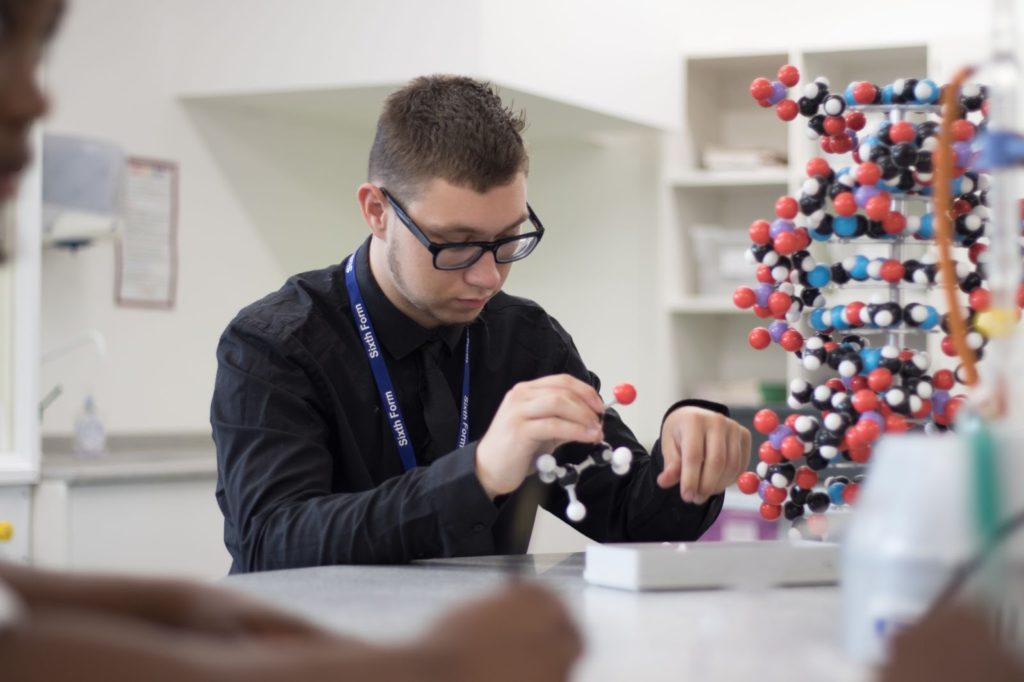 A Halley Academy Sixth Form student is shown handling a DNA sculpture in Science.